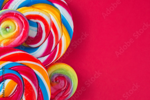 Bright and colourful candy lollipops on a red background with lots of space for text