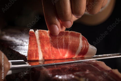Jamón ibérico de bellota español. Cortador de jamón ibérico cortando a mano loncha para degustar. Típica loncha de jamón ibérico de gran calidad con sus vetas y grasa. photo