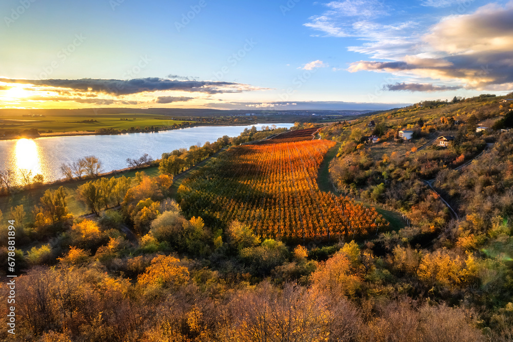 Obraz premium Idyllische herbstliche Landschaft mit bunt gefärbten Bäumen an einem See im Sonnenuntergang