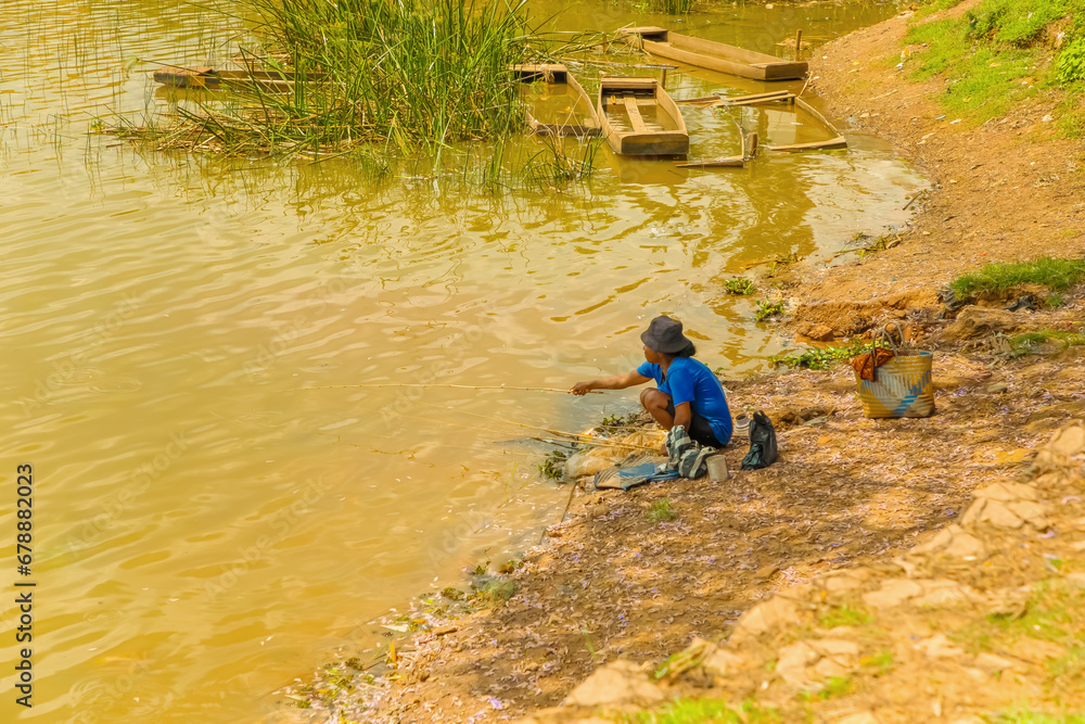 a girl squats on shore and catches fish with fishing rod. a girl squats on shore and catches fish with fishing rod.