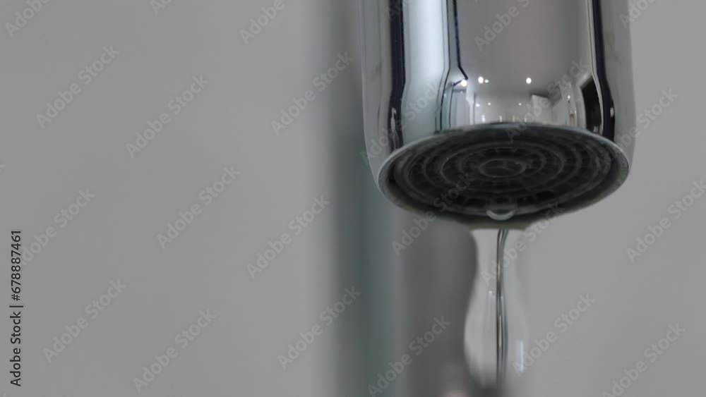 Metal faucet nozzle dripping water droplets close up macro shot. Metal faucet nozzle dripping water droplets close up macro shot.