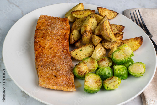 seasoned baked salmon  with potato wedges and roasted brussel sprouts, photo