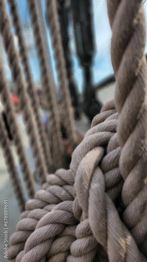 Vertical close up of ropes and rigging on an old sail ship holding up the main mast and sails