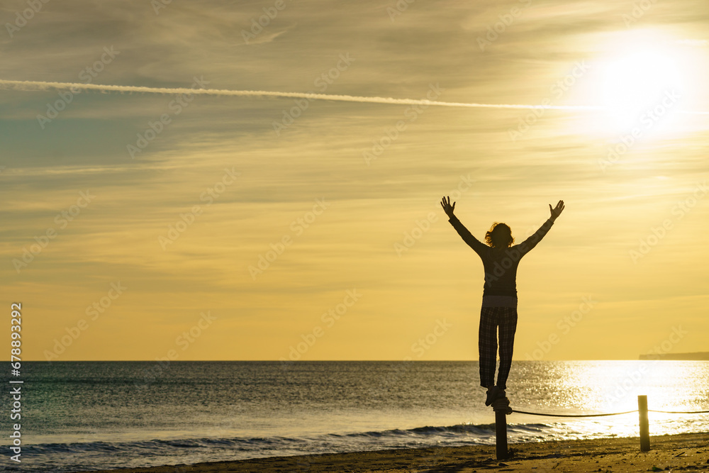 Woman on beach enjoy sunrise with arms up Woman on beach enjoy sunrise with arms up