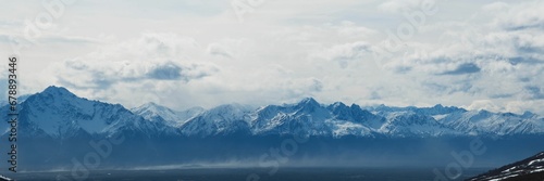 Panoramic shot of beautiful mountains under a blue cloudy sky on a sunny day