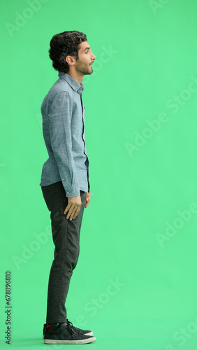 full-length portrait of a young man. standing isolated on green background