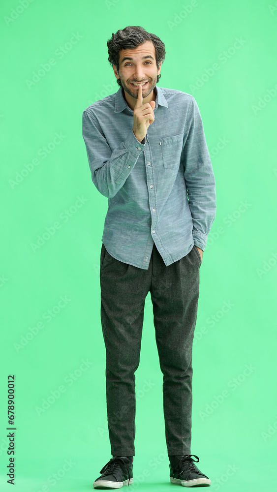 young man in full growth. isolated on green background showing with finger to keep quiet