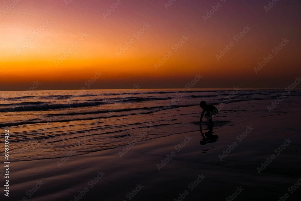 Silhouette of kid playing on beach during sunset