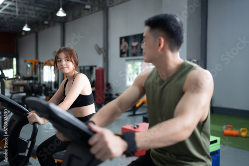 A young man and woman ride a bicycle and exercise