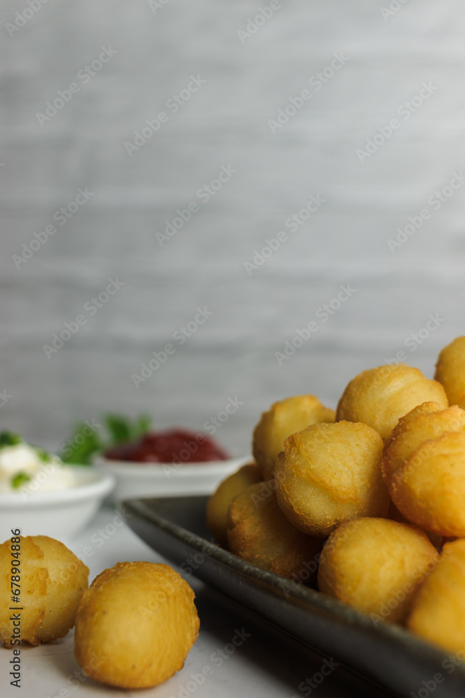 Duchess potatoes, homemade, typical in chile, with parsley, in rectangular plate, container with, ketchup, mayo, on white background, copy space, close-up, vertical. Concept of typical chilean food Duchess potatoes, homemade, typical in chile, with parsley, in rectangular plate, container with, ketchup, mayo, on white background, copy space, close-up, vertical. Concept of typical chilean food