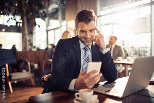 Businessman using smartphone in modern cafe photo