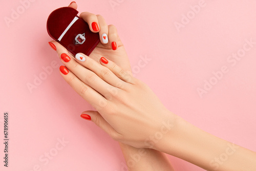 Manicured womans hands holding wedding ring. Fashionable valentines day nail design