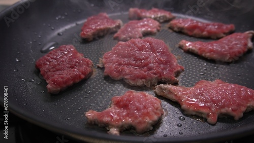 Dolly shot of Raw Steaks Cooking on Nonstick Pan.