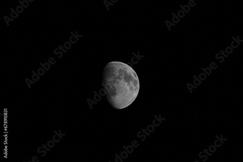 Closeup of the surface of a half moon captured in the dark sky