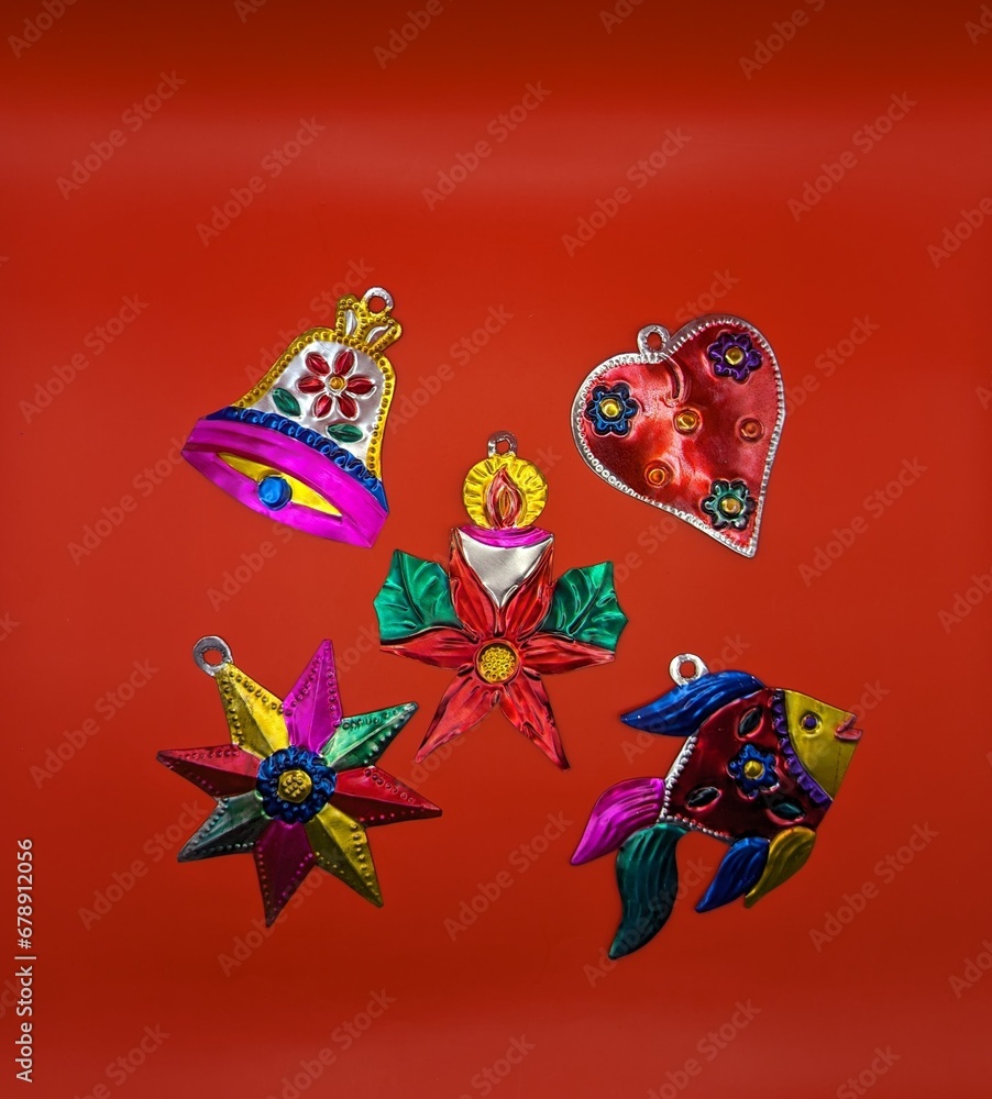 Mexican traditional tin christmas decorations, red background, centered. Fish, star, poinsettia, bell, heart