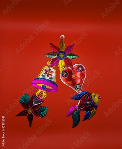 Mexican tin christmas decorations in christmas tree shape  red background  centered