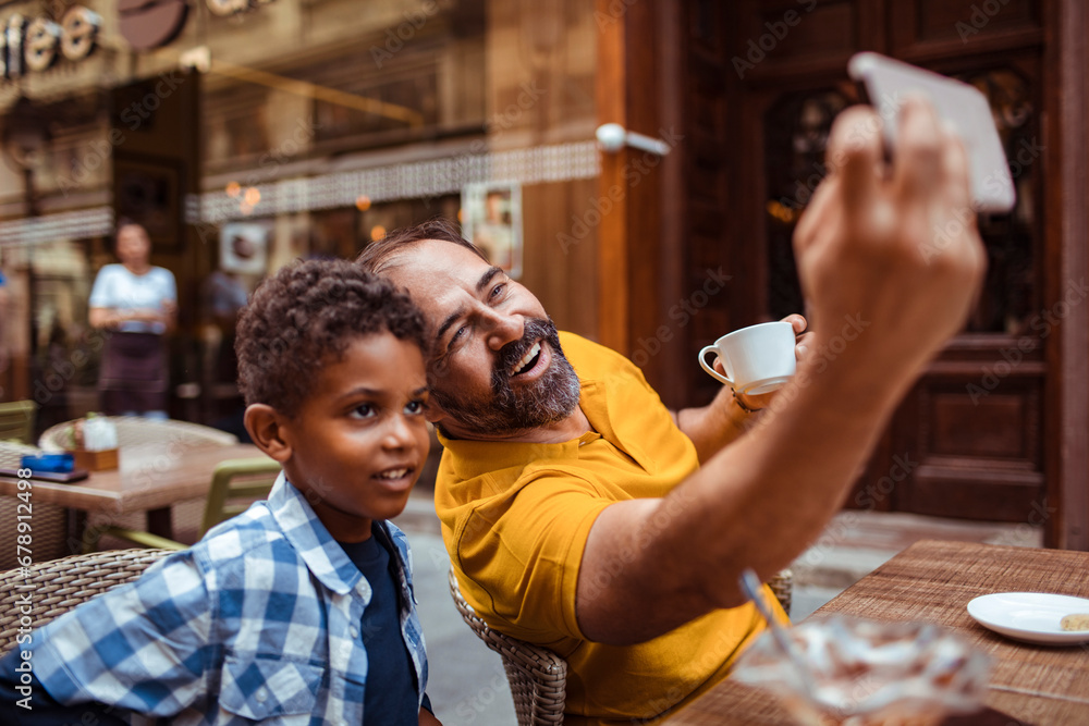 Father taking selfie with little son in public cafe