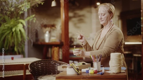 Mulher idosa sorridente apreciando o trabalho de ceramica em casa. Cinematico 4k. photo