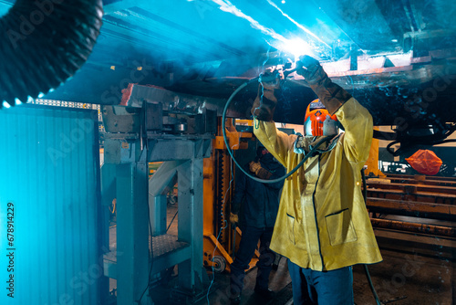 man working under a train using a welder 