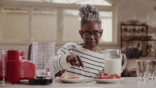 Mulher senior feliz fazendo vitamina saudavel de pela manha na cozinha de casa. Cinematico 4k. photo