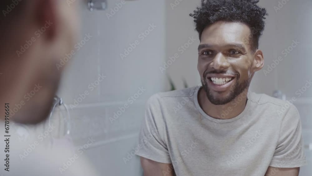 Black man looking in the bathroom mirror during his morning routine at home. Cinematic 4k. Black man looking in the bathroom mirror during his morning routine at home. Cinematic 4k.