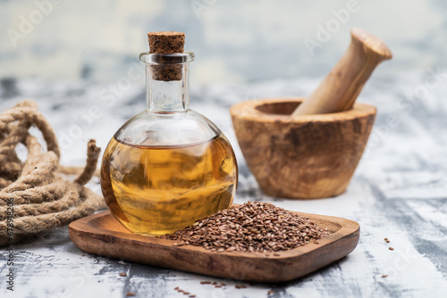 Flaxseed oil in a bottle with brown flax seeds in a wooden bowl close-up.