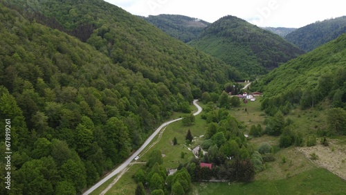 Aerial shot of a valley road between green mountains.