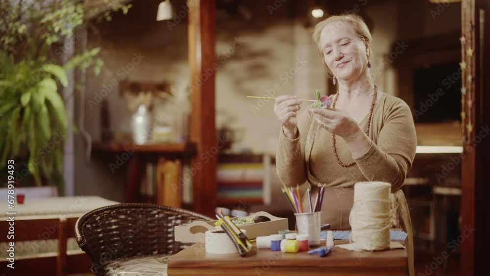 Artista senior feliz pintando um vaso de ceramica. Cinematico 4k.
