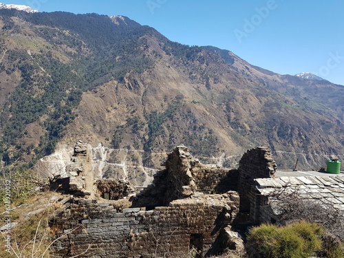 Ruins of the 52-room house in Darkot village, Uttarakhand, India with mountains in the background