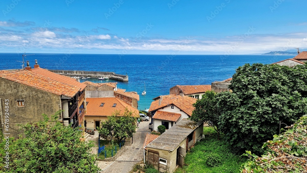 High angle shot of rural houses and greenery against a blue sea