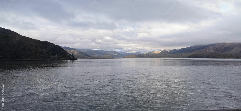 Tranquil view of a lake surrounded by mountains on a cloudy day