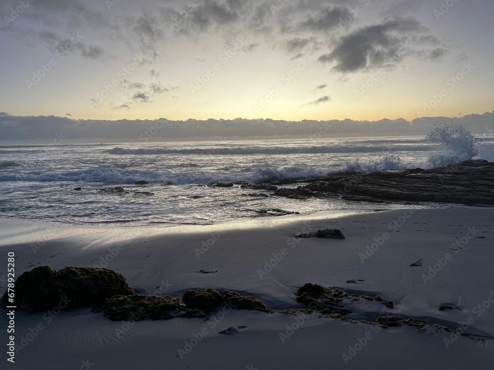 Beautiful sandy beach with splashing waves of the sea in the background at sunset Beautiful sandy beach with splashing waves of the sea in the background at sunset