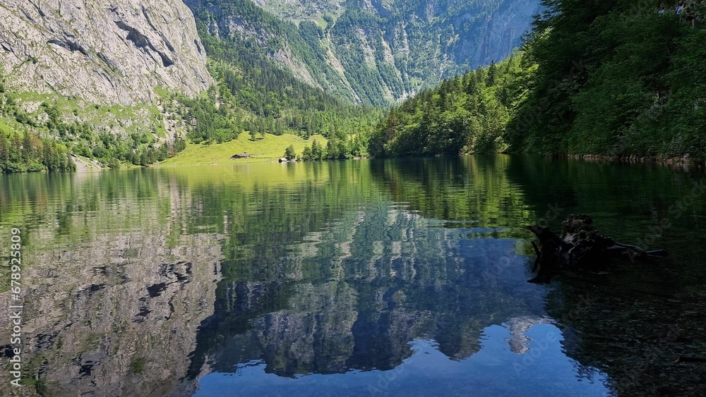Calm lake surrounded by trees and mountains reflected in the waters on a sunny day