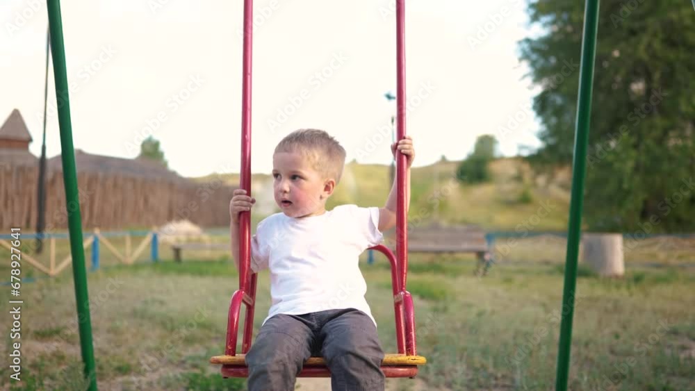 child rides on a swing in the park. happy family kid dream concept. child son swings on a swing at the playground. kid in lifestyle kindergarten playing on swing outdoors child rides on a swing in the park. happy family kid dream concept. child son swings on a swing at the playground. kid in lifestyle kindergarten playing on swing outdoors