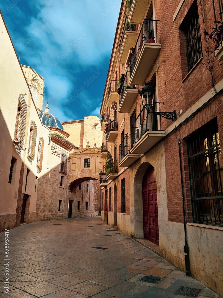 Vertical shot of an alley between old buildings under a blue sky