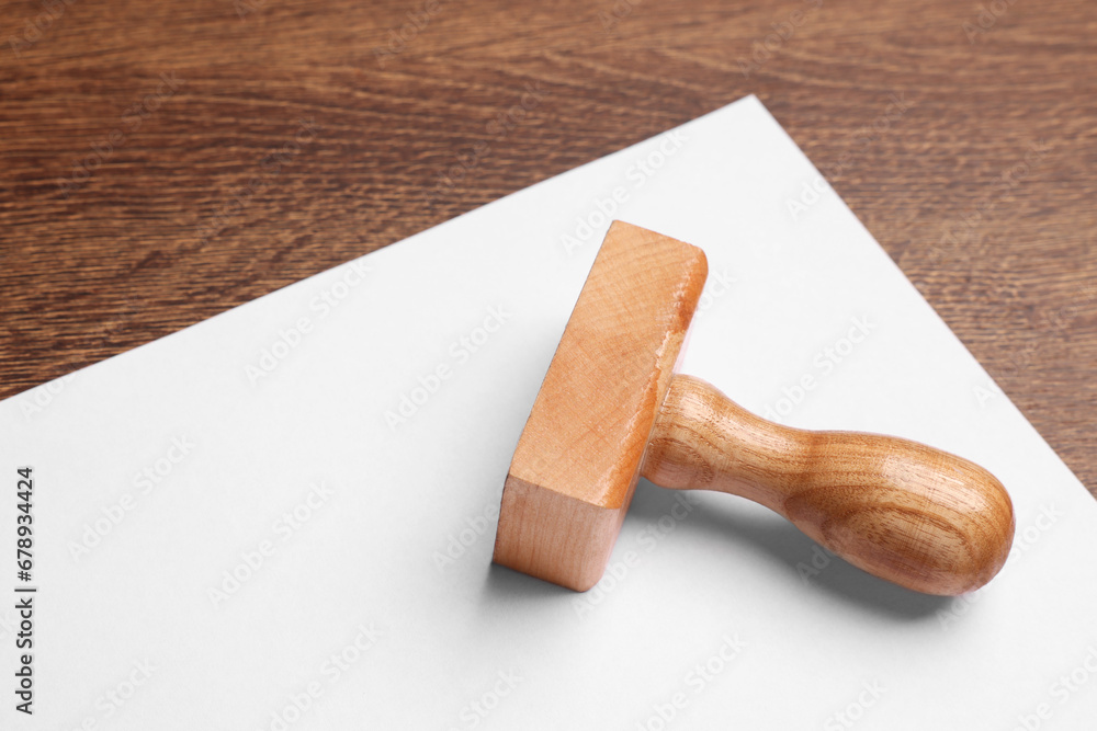 One stamp tool and sheet of paper on wooden table, closeup. Space for text