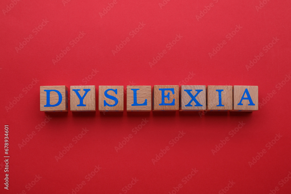 Obraz premium Wooden cubes with word Dyslexia on red background, flat lay