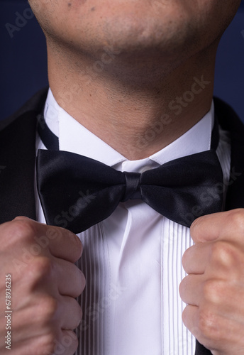 Crop anonymous male entrepreneur in classy suit adjusting tie on white blue