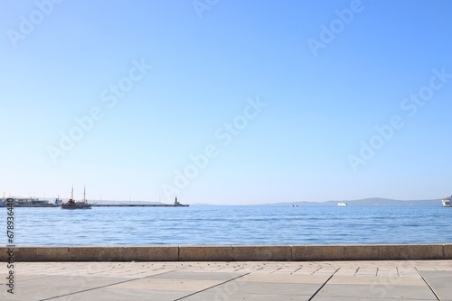 Beautiful view of embankment and calm sea with yachts on sunny day