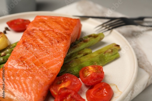 Tasty grilled salmon with asparagus and tomatoes on table, closeup