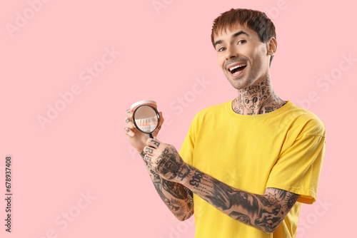 Young tattooed man magnifyi...