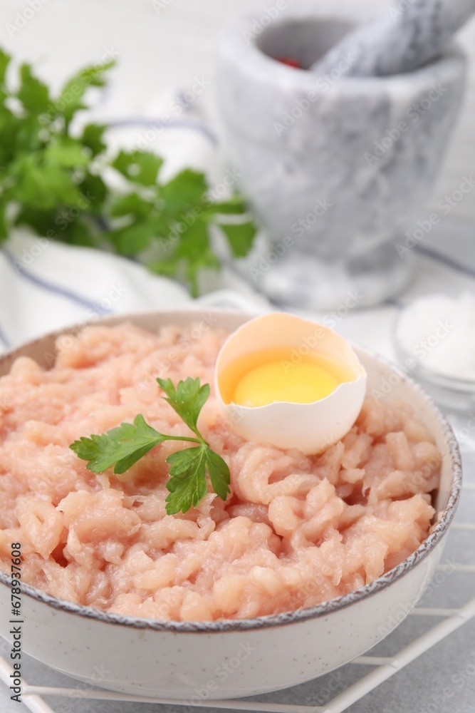 Fresh raw minced meat, parsley and egg in bowl on light grey table, closeup Fresh raw minced meat, parsley and egg in bowl on light grey table, closeup