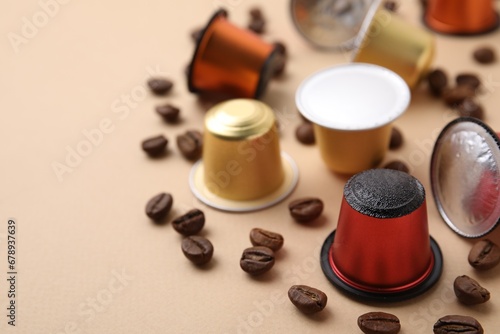 Many coffee capsules and beans on beige background, closeup. Space for text