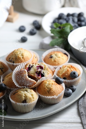 Delicious sweet muffins with blueberries on white wooden table