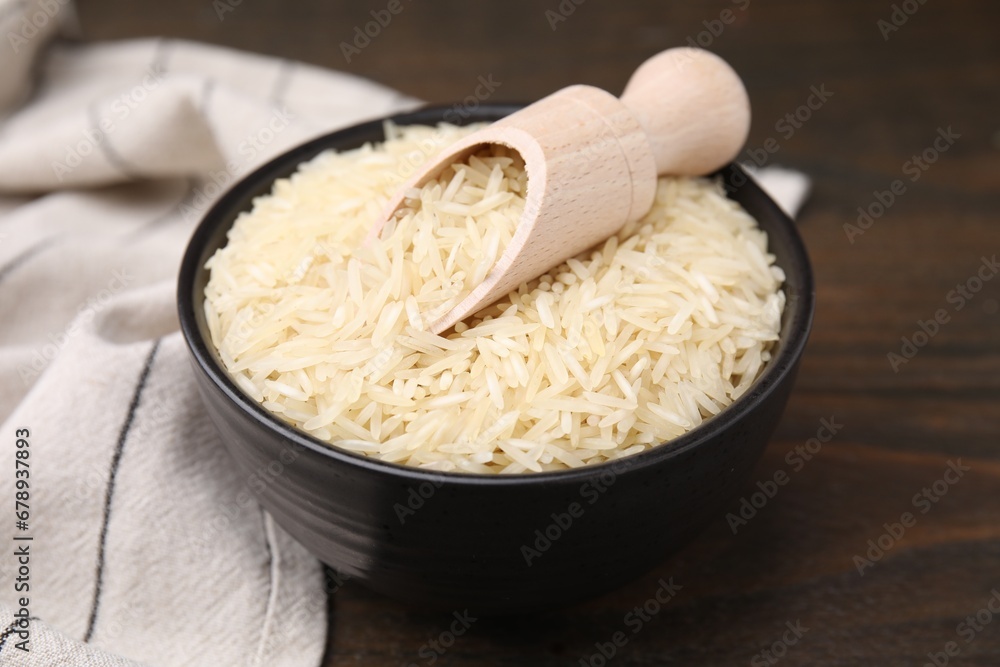 Bowl and scoop with raw rice on wooden table, closeup Bowl and scoop with raw rice on wooden table, closeup