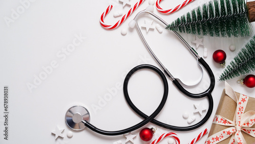 Christmas medical banner.Stethoscope,gift box,decorative Christmas trees,red balls,stars and pills on white background,top view,flat lay,copy space.New Year's medicine, congratulations to doctor.
