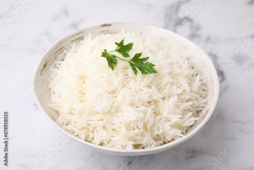 Bowl of delicious rice with parsley on light table, closeup
