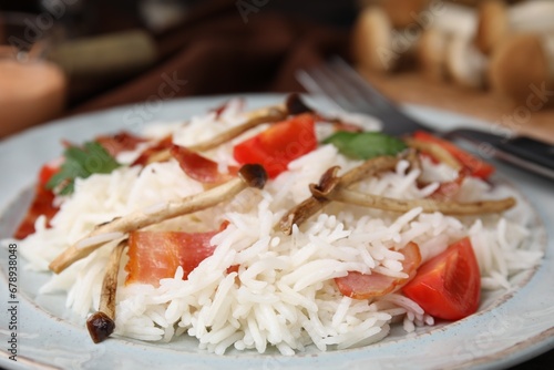 Delicious rice with bacon, mushrooms and tomatoes on table, closeup