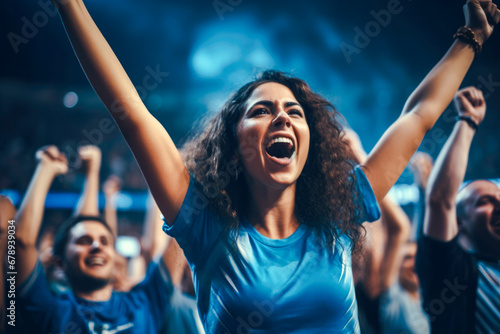 Enthusiastic female sports fan is fully immersed in the excitement of a soccer match with a high-energy crowd in background, her impassioned cheering shows the joy of sport photo