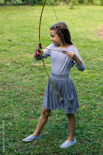 Girl archer with bow and arrow outdoors